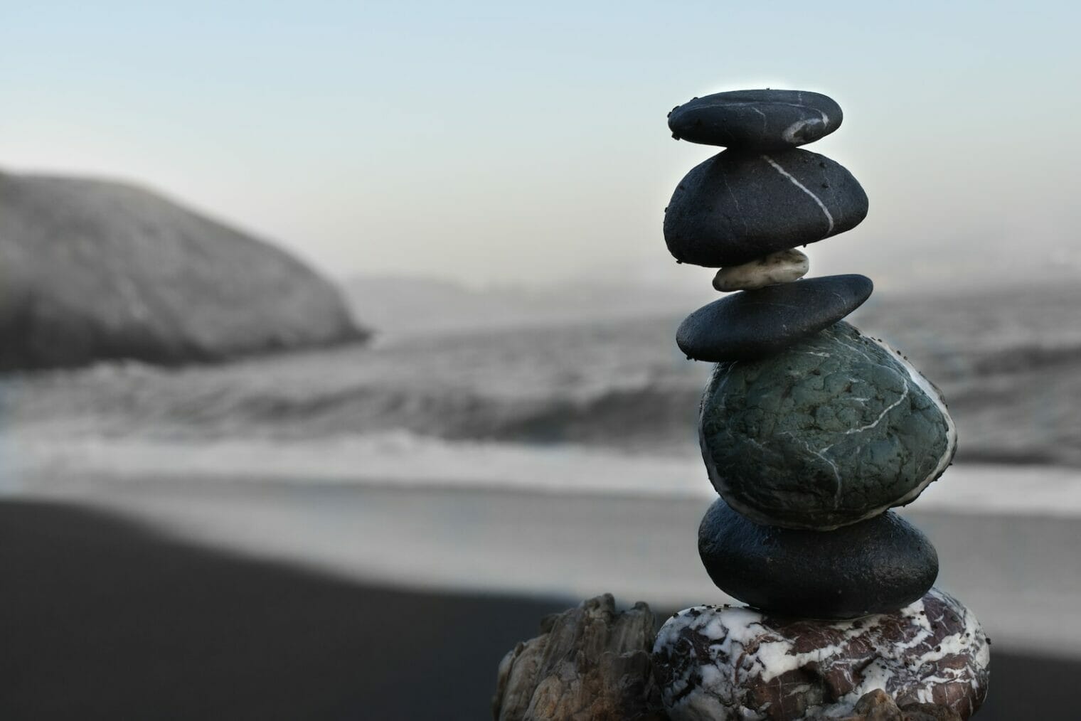 A stack of rocks on top of a piece of wood used in behavior therapy for parenting to promote mental health.