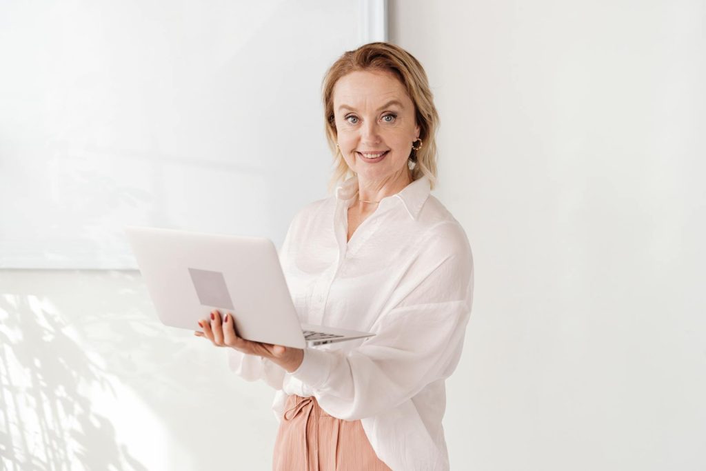 Woman in White Long Sleeve Shirt Holding a Laptop