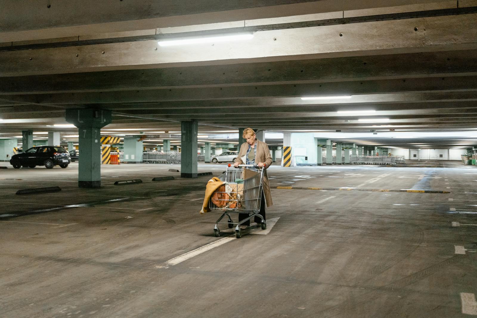 A Woman Pushing Her Car in the Parking Area