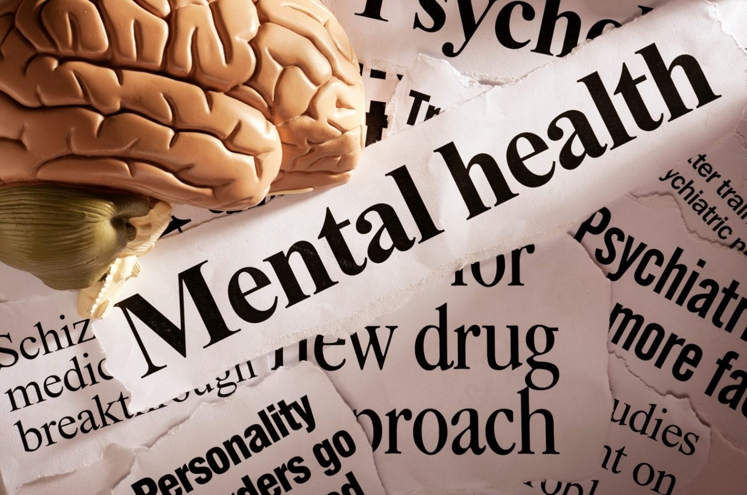 A brain and newspaper clippings with the words "Mental health"