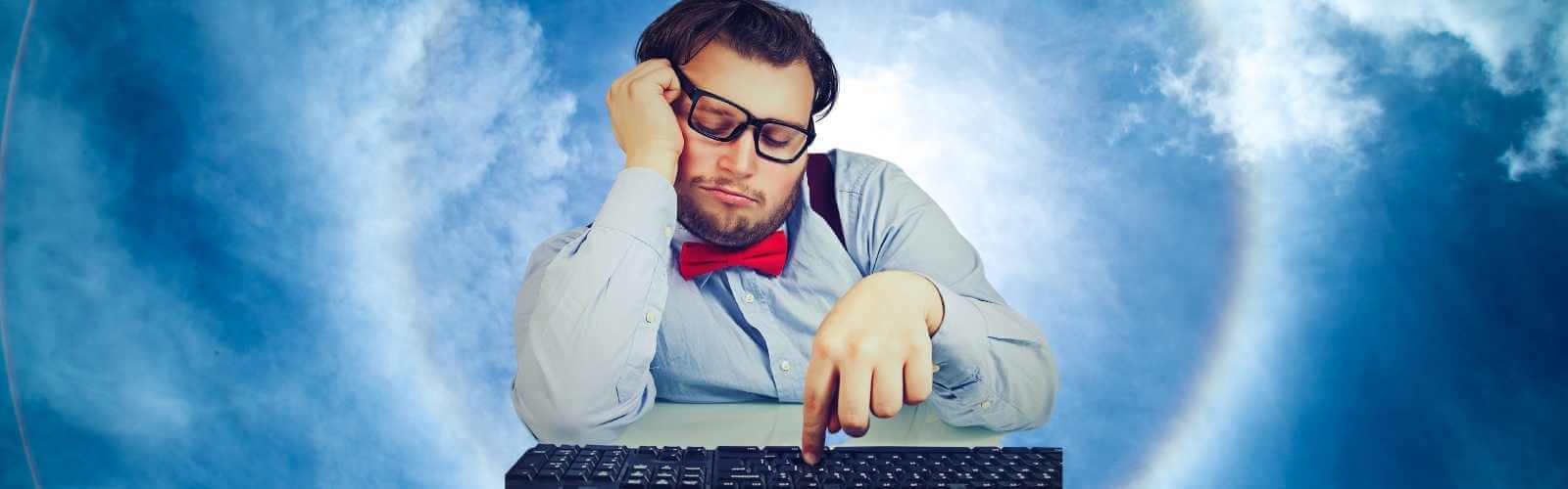 A man with glasses and a bow tie is typing on a computer.