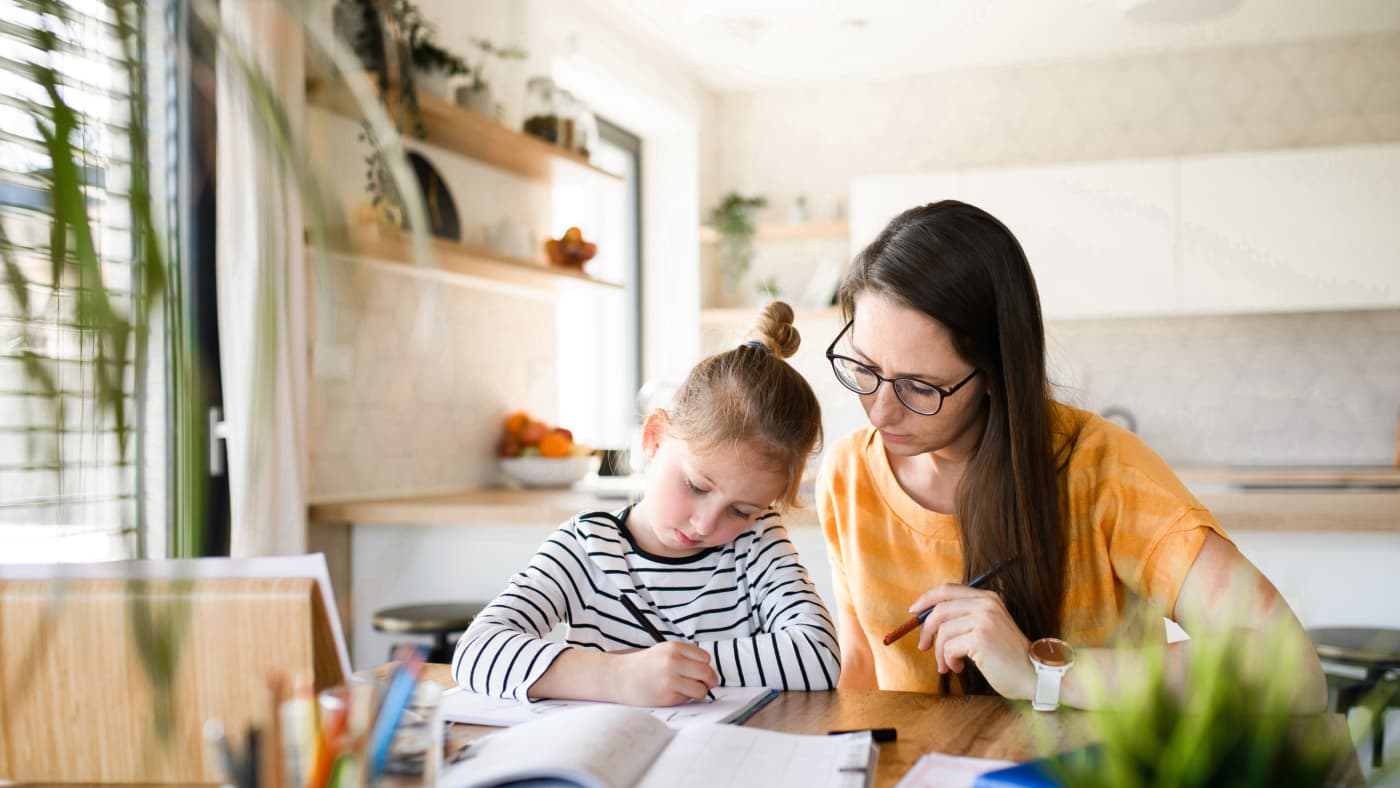 A mother helping her daughter with homework at home.