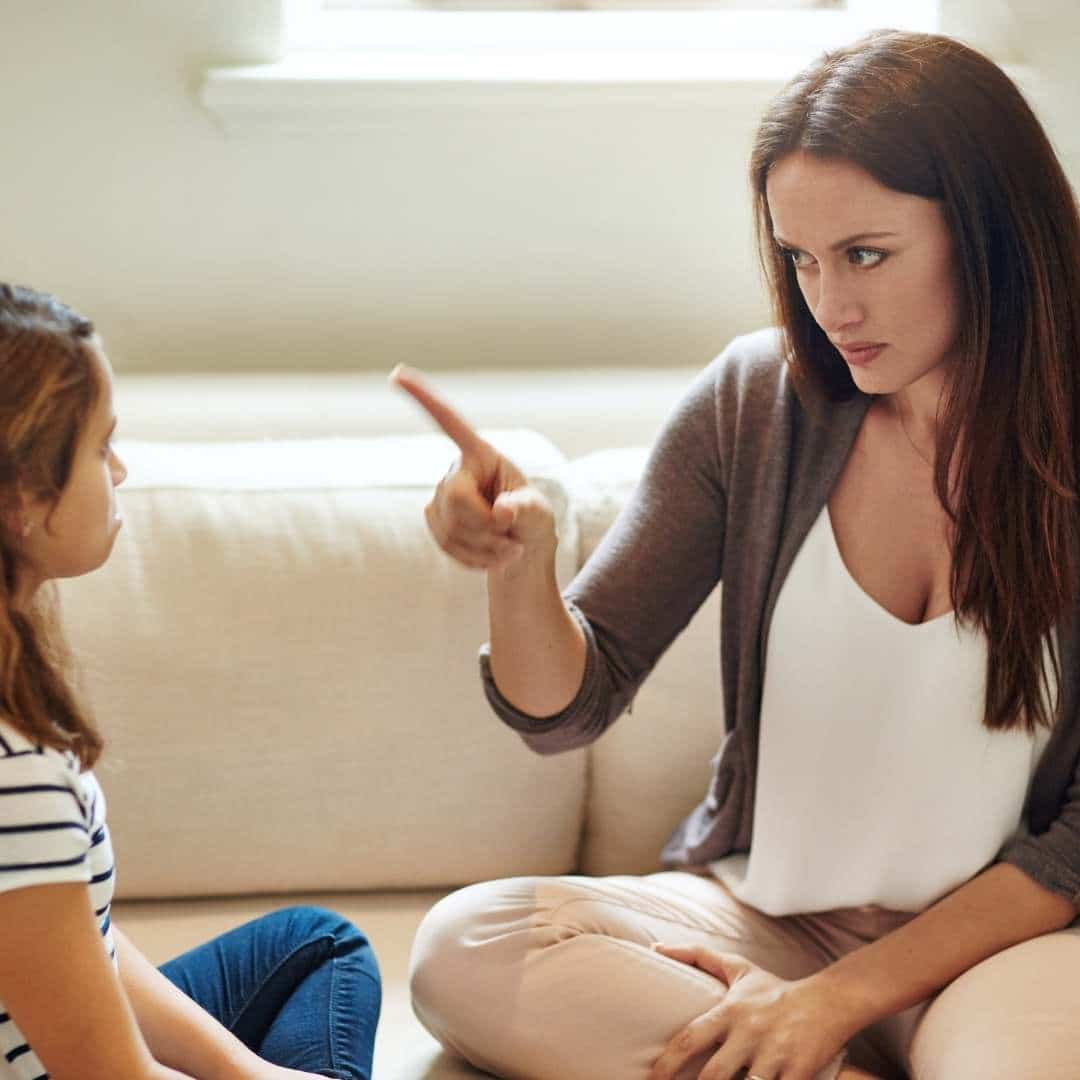 A woman talking to a young girl on a couch.