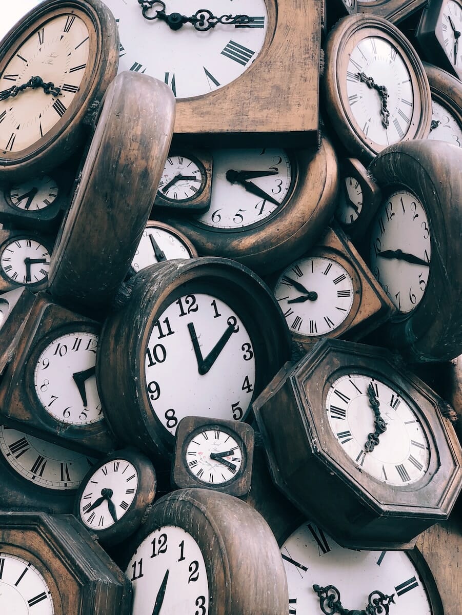 A diverse collection of clocks displaying various times, emphasizing the importance of healthcare equity and parenting.