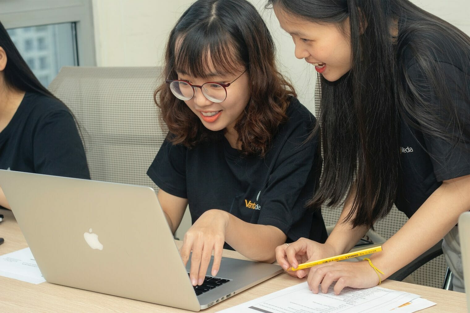 Three Asian women working on a laptop, promoting youth wellness and parenting.